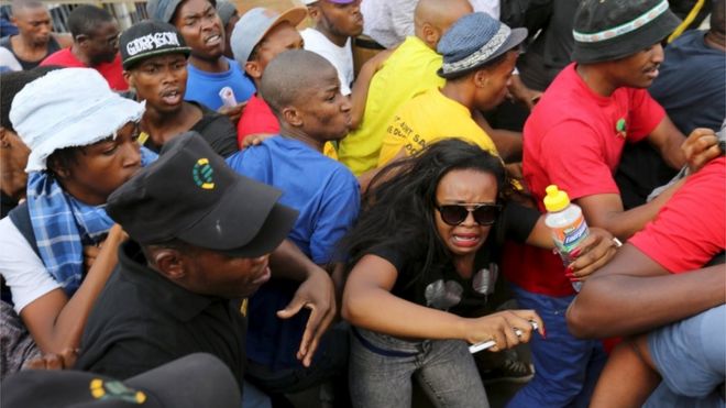 Студенты реагируют во время их столкновения с охранниками, когда они протестуют против запланированного увеличения платы за обучение за пределами университета Йоханнесбурга