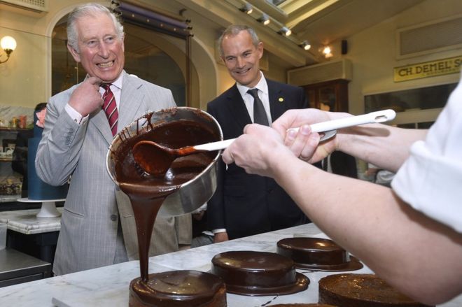 Принц Чарльз и посол Великобритании Ли Тернер смотрят, как шоколад наливается на торт