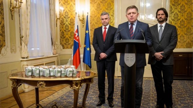 Премьер-министр Словакии Роберт Фицо (C) находится рядом с президентом Словацкой полиции Тибором Гаспаром (слева) и министром внутренних дел Словакии Робертом Калинаком (справа) рядом с пачками банкнот евро