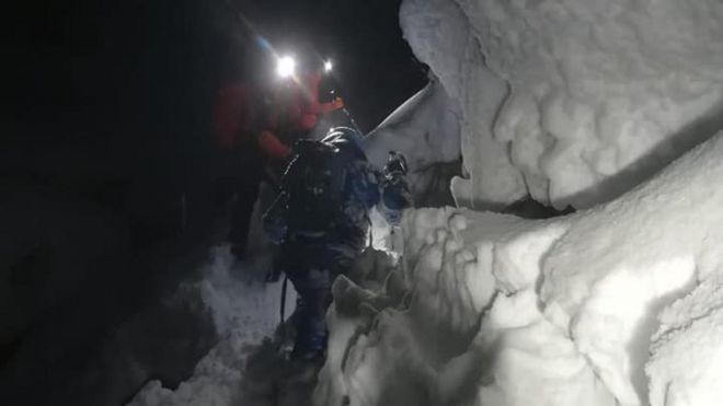 Спасатели поднимаются по глубокому снегу, чтобы добраться до польского сноубордиста