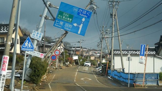 道路標識や電柱が傾き、路面が隆起する被災地（8日、石川県内灘町）