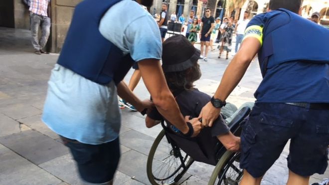 Police help a man in a wheelchair to leave the area around the Ramblas