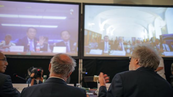 Австрийские ученые сидят перед двумя экранами во время рекордного видеозвонка с китайскими учеными