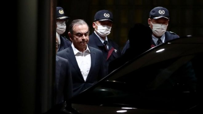 Карлоса Гона сопровождают, когда он выходит из Токийского изолятора временного содержания после его освобождения под залог в Токио в апреле 2019 года