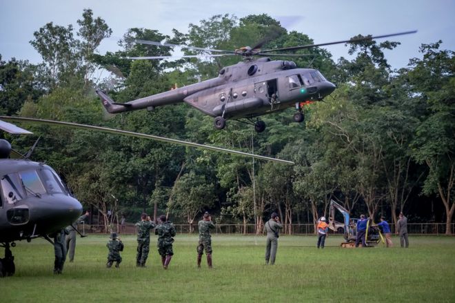 Военно-воздушные силы Таиланда заглядывают на вертолете на поляну в лесу возле возможного надземного проема в пещеру Тхам Луанг