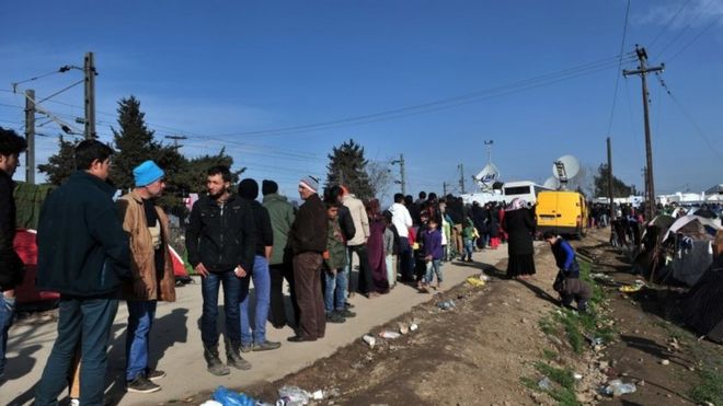 Мигранты и беженцы стоят в очереди за едой, ожидая пересечения границы между Грецией и Македонией, недалеко от деревни Идомени (02 марта 2016 г.)