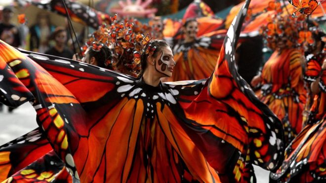 Женщины, одетые как бабочки, танцуют во время парада