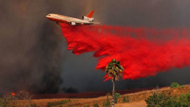 Самолет DC-10 сбрасывает огнезащитный состав на возгораемый ветром лесной пожар в Оранже, штат Калифорния
