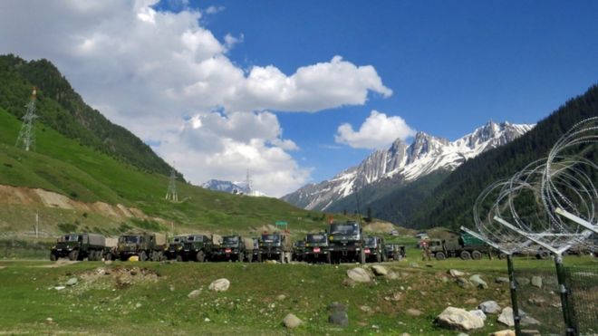 Indian army soldiers walk past their parked trucks at a makeshift transit camp before heading to Ladakh, near Baltal, southeast of Srinagar,16 June 2020
