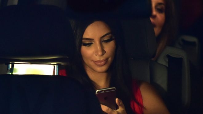 Ким Кардашьян проверяет телефон в машине