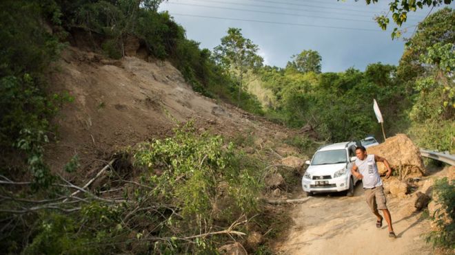 Vehicles drive along a road affected by a landslide on the outskirts of Palu in Central Sulawesi on September 29, 2018