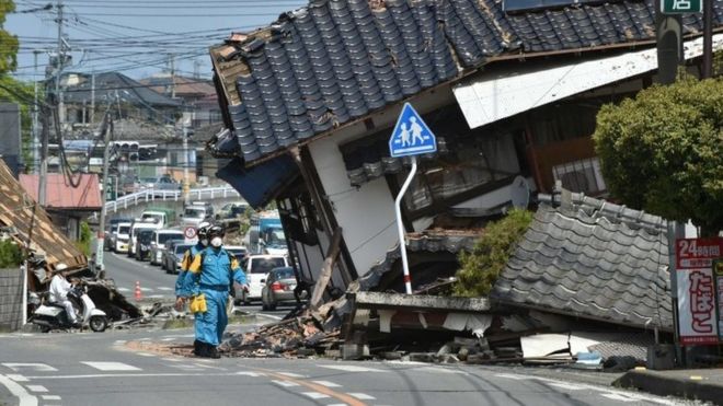 Полицейские разыскивают пропавших людей в поврежденном районе после землетрясений-близнецов в Машики, префектура Кумамото (17 апреля 2016 года)