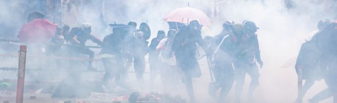 Протестующие на фоне слезоточивого газа во время демонстрации Политехнического университета Гонконга