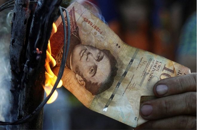 Мужчина сжигает счет в 100 боливаров во время акции протеста в Эль-Пинале, Венесуэла, 16 декабря 2016 года.