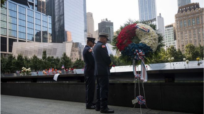 Two firefighters pay their respects during a commemoration ceremony for the victims of the September 11 terrorist attacks at the National September 11 Memorial