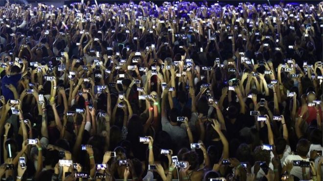 Поклонники используют свои телефоны на концерте