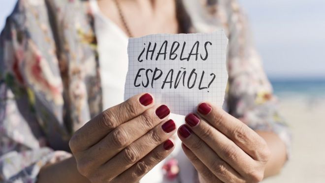 Una mujer sostiene un papel que pregunta: ¿hablas español?