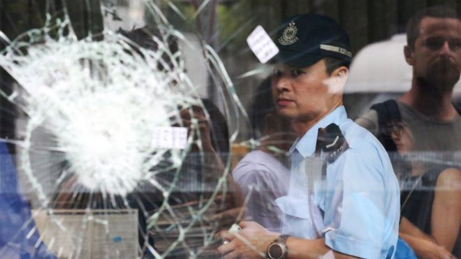 Hong Kong police officer seen through shattered glass