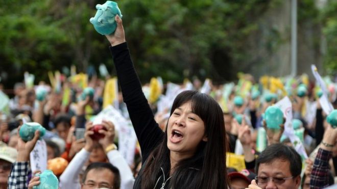 Сторонник Цай Инь-вэнь (не на фото), председатель от главной оппозиционной Демократической прогрессивной партии Тайваня (DPP) и кандидат от партии на президентских выборах в январе 2016 года, держит копилку на сбор средств партии