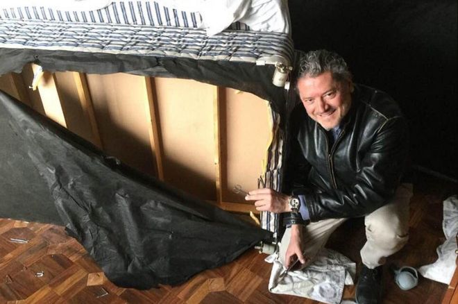 Vasileios Vasileiou next to the bed he hid inside while Taliban gunmen operated from his room