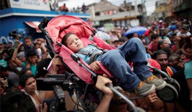 Гондурасские мигранты задерживают ребенка в багги, собираясь на границе с Гватемалой
