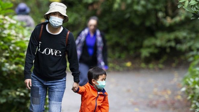 Una familia en Vancouver caminando al aire libre con mascarillas puestas