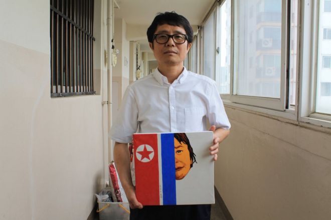 Сонг Беок держит одну из своих пропагандистских работ в Северной Корее