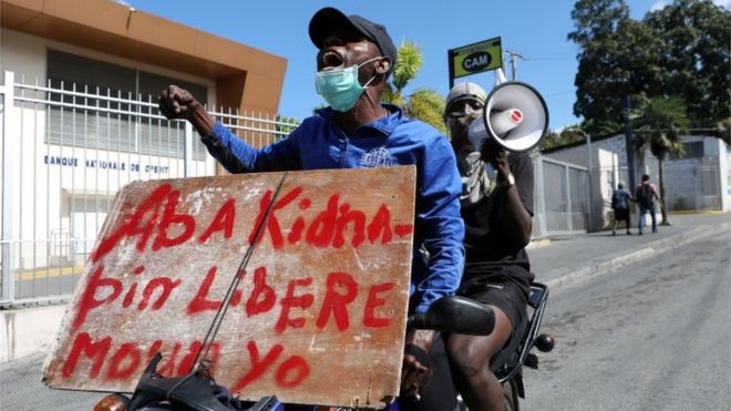 A protester on a motorcycle carries a sign reading "Down with kidnappings. Free the people" during demonstrations against widespread kidnappings, in Port-au-Prince, Haiti November 25, 2021