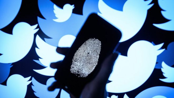 A thumbprint is displayed on a mobile phone as the logo for the Twitter social media network is projected onto a screen on August 09, 2017 in London, England