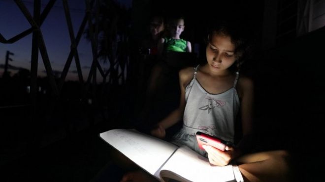 Una joven de Guanajay (al oeste de La Habana) usa la linterna de su teléfono móvil para estudiar.