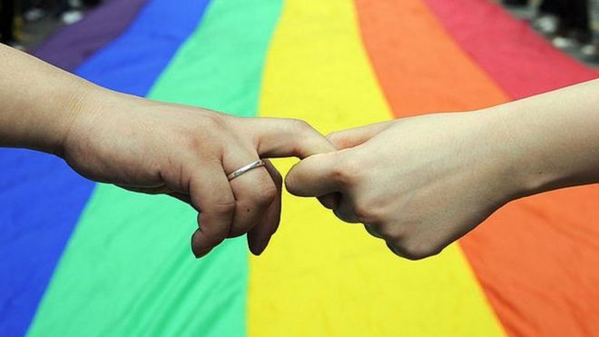 Hands being held in front of giant rainbow flag, Hong Kong