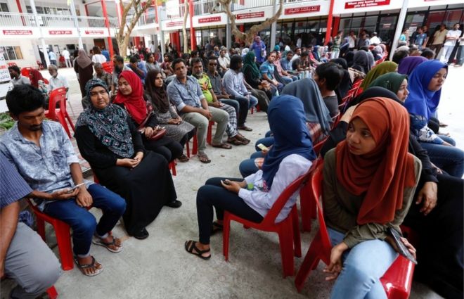 Люди сидят в очереди и ждут, чтобы отдать свои голоса на избирательном участке во время президентских выборов в Мале, Мальдивы