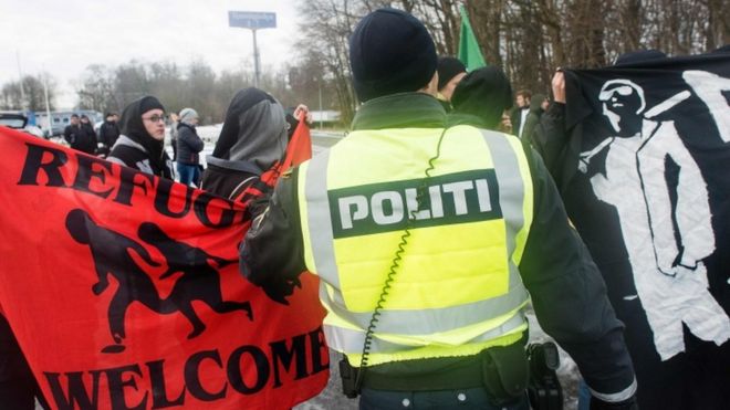 Полицейский пытается разлучить протестующих против мигрантов и против мигрантов на датско-германской границе 9 января 2016 года в Крусаа, Дания