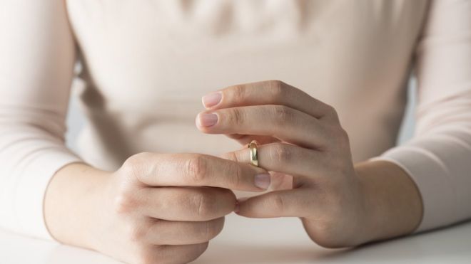 Mujer sacándose alianza matrimonial.