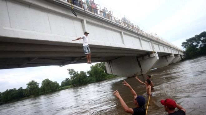 Гондурасский мигрант, часть каравана, пытающегося добраться до США, прыгает с моста, соединяющего Мексику и Гватемалу, чтобы избежать пограничного контрольно-пропускного пункта в Сьюдад-Идальго, Мексика, 19 октября 2018 года