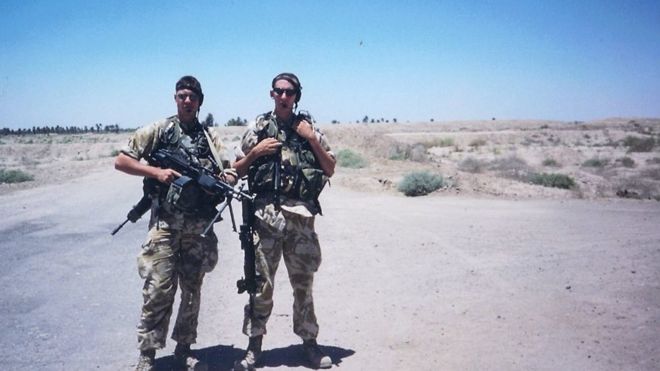 Двое мужчин в военной форме стоят с автоматами в пустой пустыне / поле