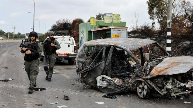 以色列南部阿什克伦（Ashkelon）以军士兵走过一辆被烧焦汽车（10/10/2023）