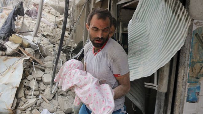 Un hombre carga un bebé cubierto tras un ataque en Alepo, Siria