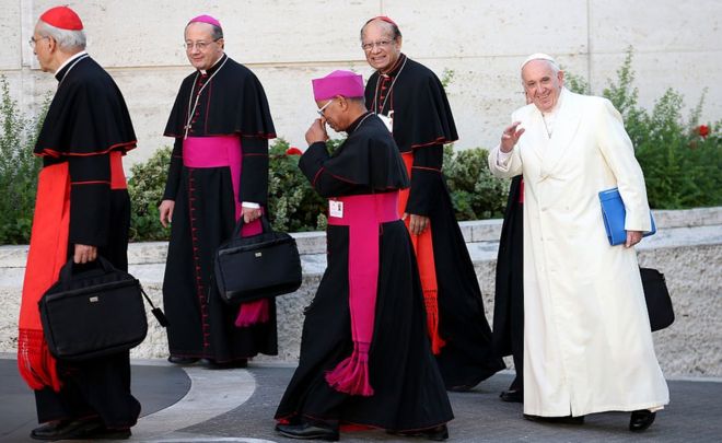 24 октября 2015 года Папа Римский Франциск, в окружении архиепископа Бомбея, кардинала Освальда Грасиаса (слева) и других епископов, прибывает в Синодальный зал Ватикана.