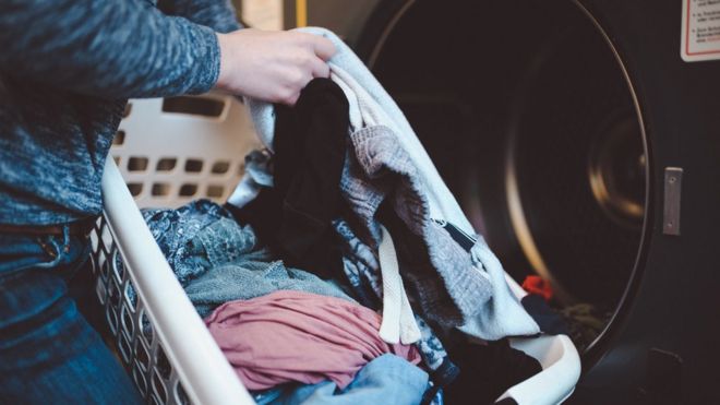 Una persona pone ropa en la lavadora