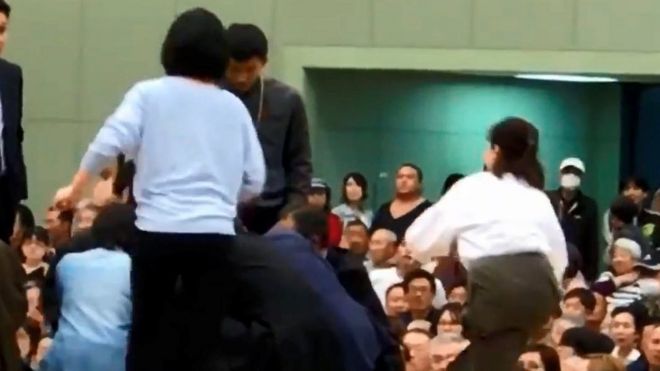 Снимок с видео на Youtube показывает, как женщины взбираются на кольцо сумо для лечения мэра города Майдзуру Риозо Татами, который рухнул во время выступления в спортзале в Майдзуру, префектура Киото, Япония, 4 апреля,