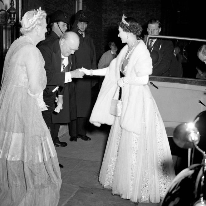 Премьер-министр сэр Уинстон Черчилль кланяется королеве Елизавете II, приветствуя ее и герцога Эдинбургского на Даунинг-стрит 10 на ужин