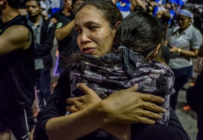 Мать и дочь обнимаются после того, как один из одноклассников дочери, 15-летний Альваро Конрадо, умер после того, как его ударила полицейская пуля в шею, когда он доставил воду протестующим студентам в Манагуа в апреле 2018 года.