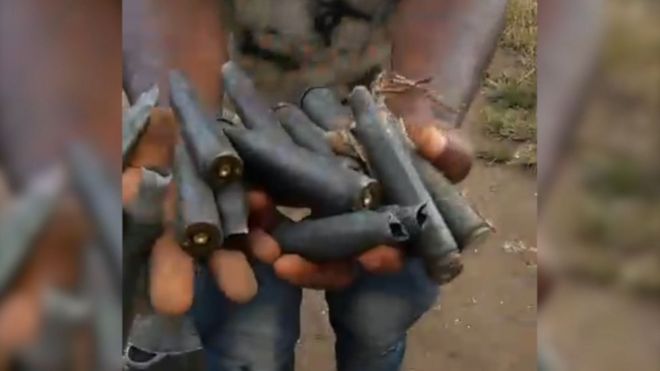 Мужчина в Кукэ Мбомо держит патроны с боеприпасами, которые, по его словам, были принесены, чтобы убивать мирных жителей