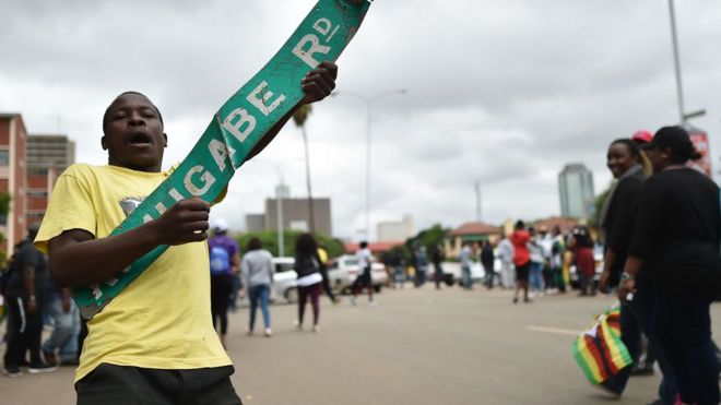 Мужчина реагирует с надписью «Роберт Мугабе-роуд» во время демонстрации, идущей в сторону Государственного дома, требуя отставки президента Зимбабве 18 ноября 2017 года в Хараре