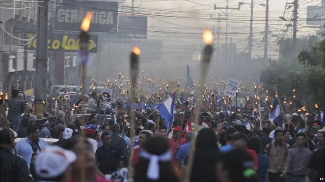 Протестующие идут в офис генерального прокурора, чтобы потребовать отставки президента Хуана Орландо Эрнандеса в Тегусигальпе 19 июня 2015 года.