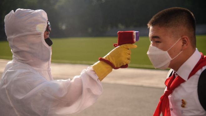 Un agente tomándole la temperatura a un alumno como parte de los procedimientos anti covid-19 en Pyongyang el 22 de junio de 2021.