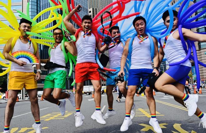 Participants jump in a pose while taking part in the annual Pride parade in Taipei