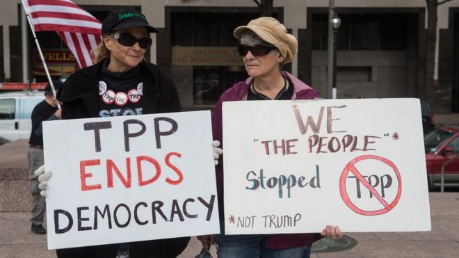 Люди держат в руках знаки протеста против торгового соглашения Транстихоокеанского партнерства