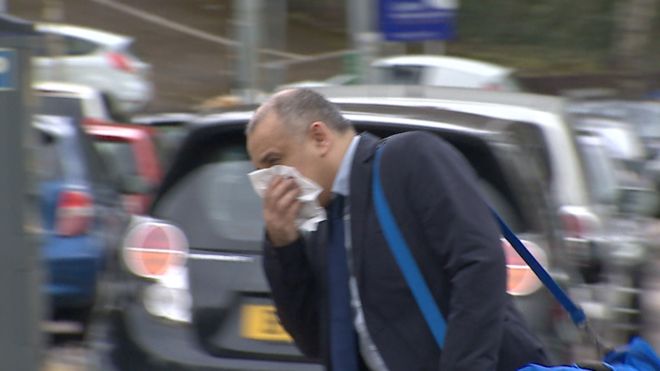 Rajesh Lama arriving at Newport Crown Court - he is trying to hide his face with a tissue. He is wearing a suit and had a blue holdall bag over his shoulder